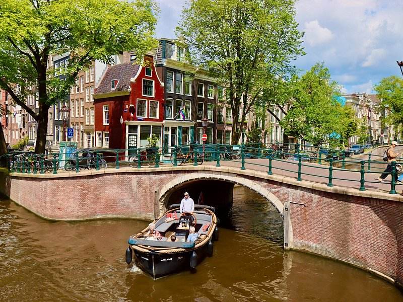 A small open boat coming through a brick canal bridge in Amsterdam