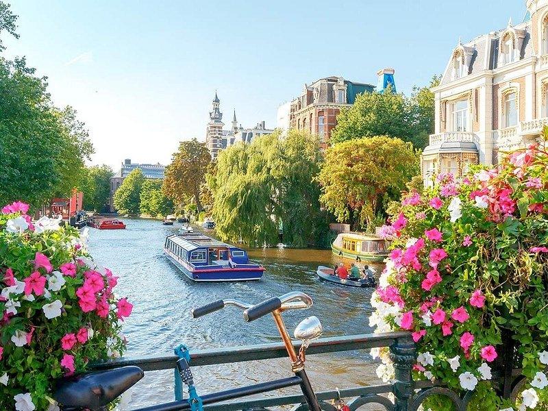 A tour boat passing under flowers on a bridge in the Amsterdam canal ring