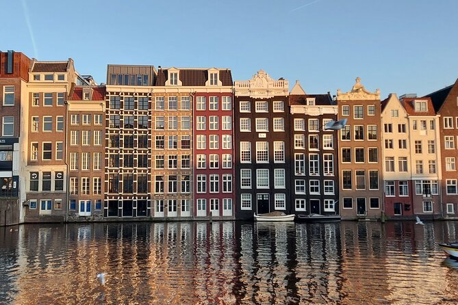 The leaning canal houses along the Damrak, reflected in still water